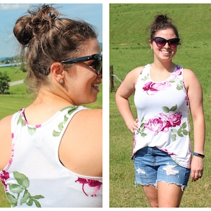 May include: A white tank top with a floral print featuring pink roses and green leaves. The tank top has a scoop neck and a racerback style.