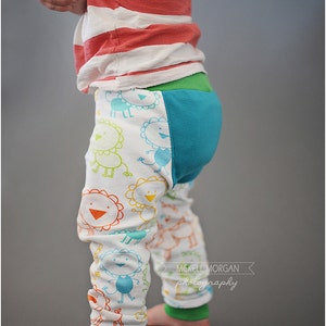May include: A toddler wearing a red and white striped shirt and colorful pants with a lion print. The pants have a turquoise and green panel on the back. The text "McKell Morgan photography" is visible in the lower right corner of the image.
