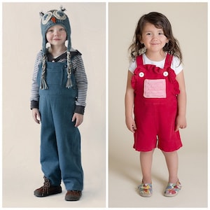 May include: Two children wearing overalls. The child on the left is wearing a blue denim overall with an owl-shaped hat. The child on the right is wearing a red overall with a pink pocket and white ruffle trim.