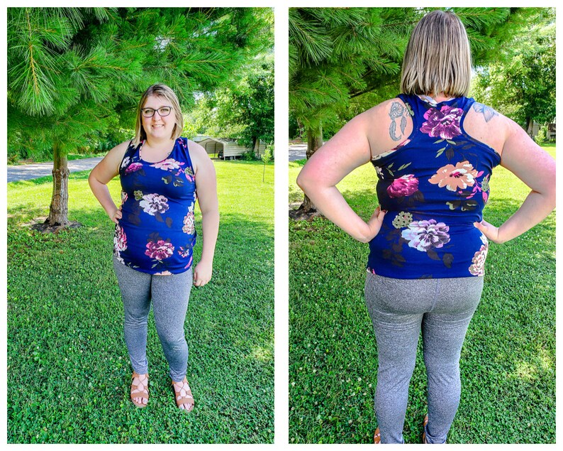 May include: A woman wearing a navy blue tank top with a floral print and gray leggings. The tank top has a racerback style.