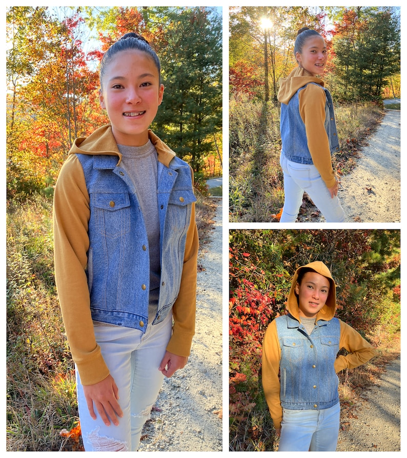 May include: A denim jacket with a mustard-colored hood and sleeves. The jacket has a button-up front and is worn over a gray shirt and light-wash jeans. The background features a path and trees with fall foliage.