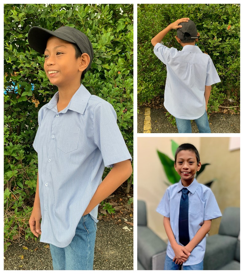 Puede incluir: Una camisa de manga corta a rayas azules y blancas con cuello abotonado y un bolsillo en el pecho izquierdo. La camisa la lleva puesta un joven que lleva una gorra de b&eacute;isbol negra y unos vaqueros azules.