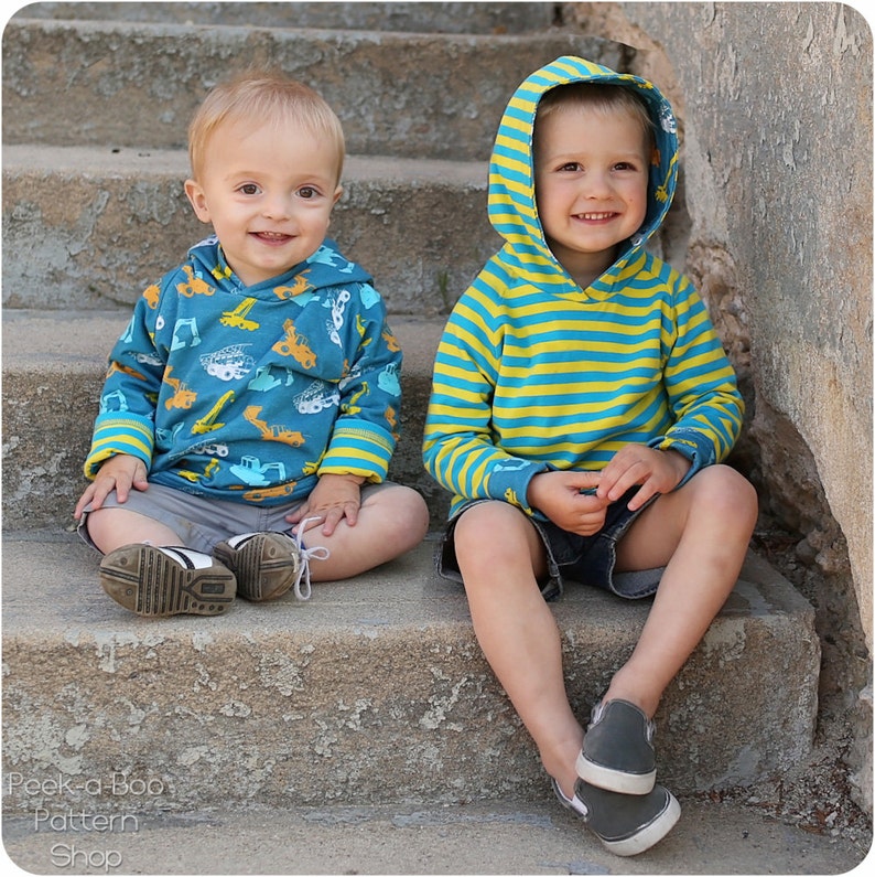 May include: Two young boys wearing hooded sweatshirts. The boy on the left is wearing a blue sweatshirt with a yellow and white construction vehicle pattern. The boy on the right is wearing a blue and yellow striped sweatshirt. Both boys are sitting on a set of concrete stairs.