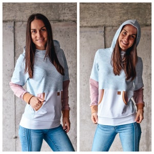 May include: A light blue hooded sweatshirt with a white and light blue patterned design. The sweatshirt has a white pocket on the front and a brown trim around the pocket.