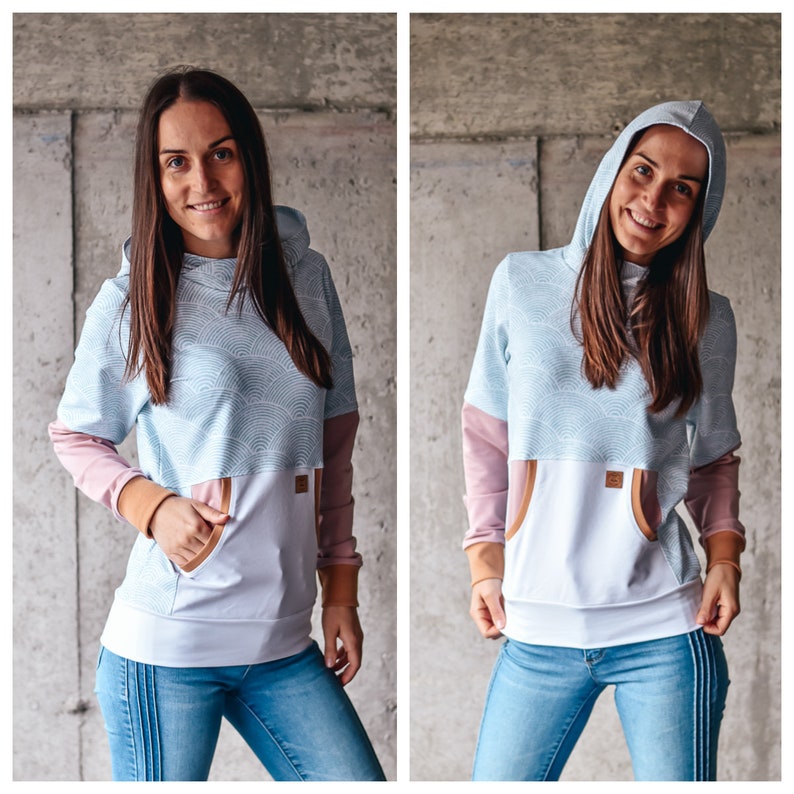 May include: A light blue hooded sweatshirt with a white and light blue patterned design. The sweatshirt has a white pocket on the front and a brown trim around the pocket.