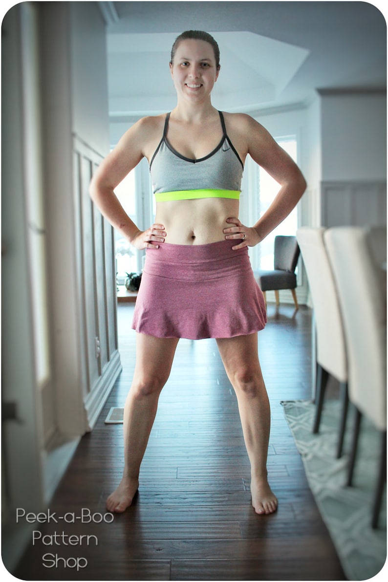 May include: A woman wearing a gray sports bra with a neon green band and a pink athletic skirt. The image also shows a dark wood floor and the text "Peek-a-Boo Pattern Shop".