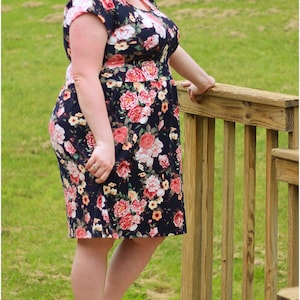 May include: A woman wearing a floral print dress with short sleeves and a scoop neck. She is standing on a wooden deck with a railing. The text "Dashing & Darling Custom Creations" is visible in the lower right corner of the image.