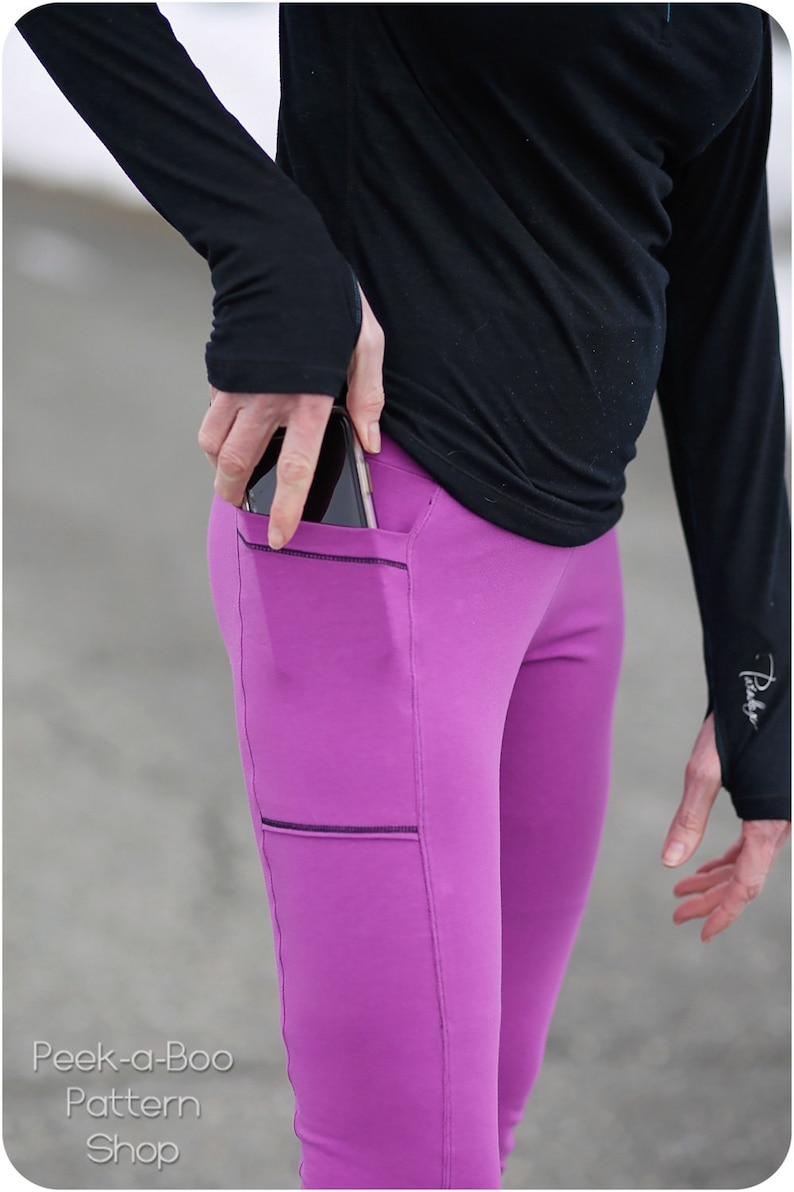 May include: Close-up of magenta leggings with black stitching and pockets. A person wearing a black long-sleeve shirt is putting a smartphone into the pocket. The leggings are part of the Peek-a-Boo Pattern Shop.