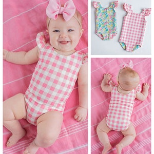 May include: Two baby swimsuits, one with a pink and white gingham pattern and the other with a floral pattern. Both swimsuits have ruffled sleeves.