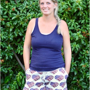 Pu&ograve; includere: Una donna indossa una canotta blu navy e pantaloncini bianchi con un motivo a cuore rosso, bianco e blu. I pantaloncini hanno una vita con coulisse.