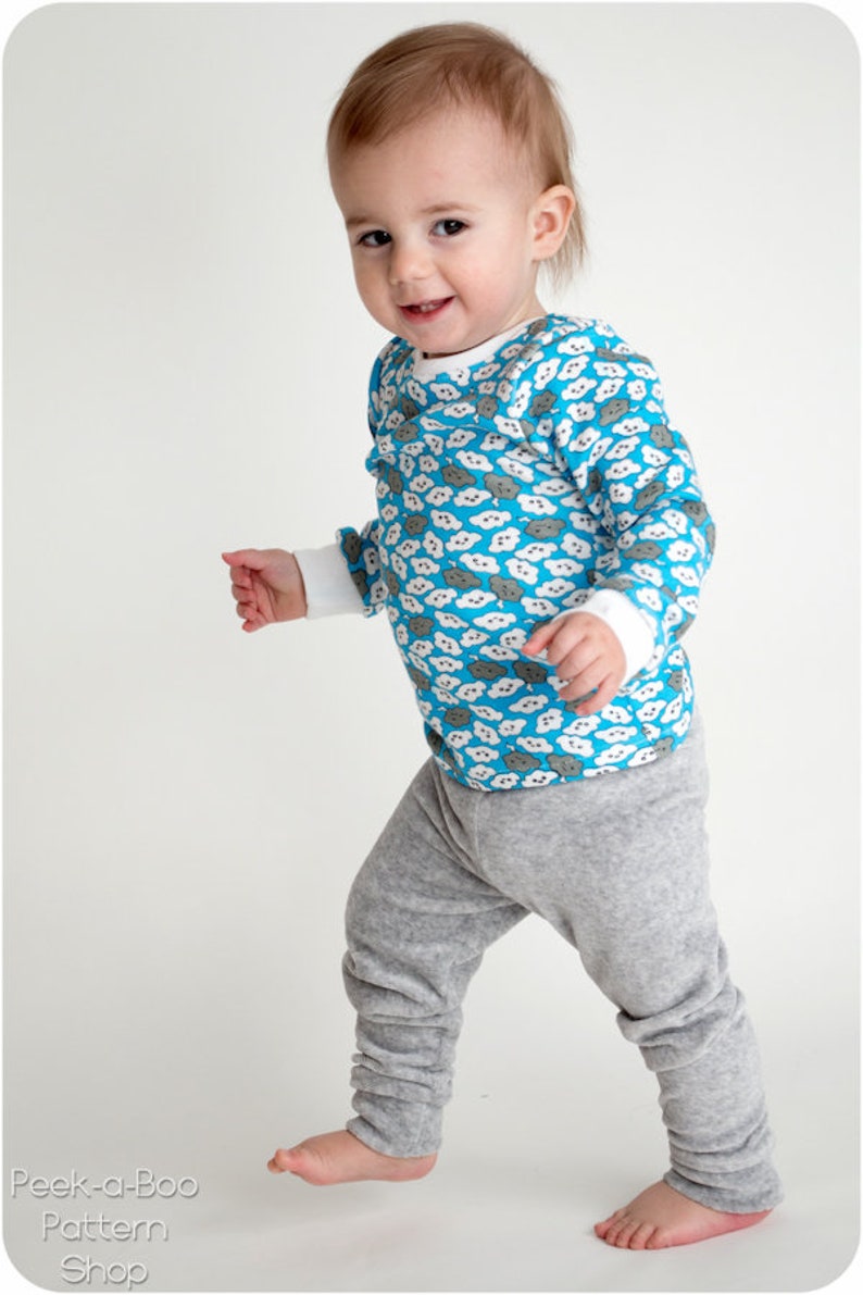 Puede incluir: Un ni&ntilde;o peque&ntilde;o con una camisa azul de manga larga con un estampado de nubes blancas y pantalones de ch&aacute;ndal grises. La camisa tiene un cuello redondo y los pantalones de ch&aacute;ndal tienen un corte holgado.