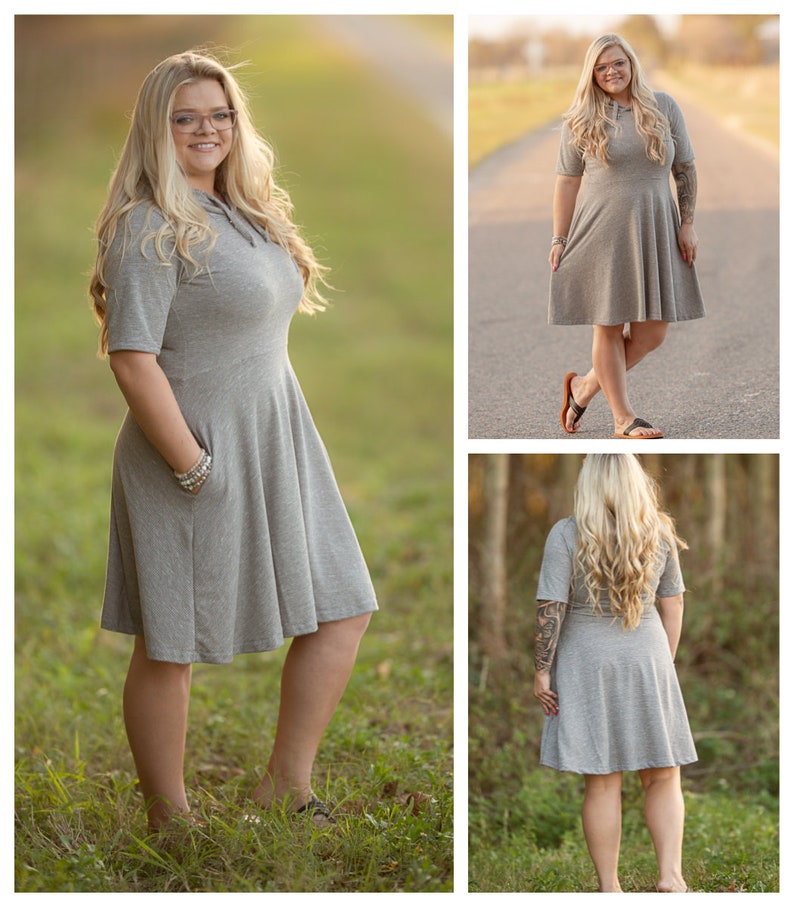Pode incluir: Uma mulher vestindo um vestido cinza de manga curta com capuz, com um corpete justo e uma saia rodada. O vestido tem um bolso do lado esquerdo. A mulher est&aacute; em p&eacute; em um campo gramado.