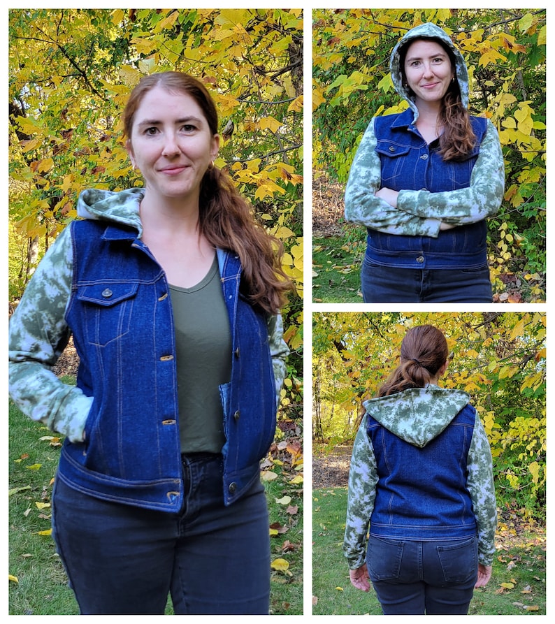 May include: A blue denim hooded jacket with green and white camouflage sleeves. The jacket has a button-up front and pockets. The person in the image is wearing a green shirt and black jeans. The background features fall foliage.