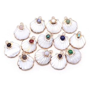 May include: A collection of white seashell charms with gold-colored trim and various gemstone accents. Each charm features a different colored gemstone, including pink, blue, green, and brown. The charms are arranged on a white background.