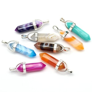 May include: A selection of gemstone pendants in shades of purple, blue, orange, and pink. Each pendant features a silver-coloured metal cap and loop for a chain. The gemstones have a polished, crystalline appearance, suitable for jewellery.