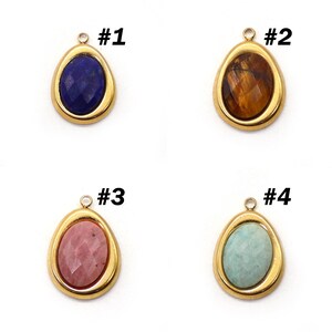 May include: Four teardrop-shaped pendants with gold-colored frames. Each pendant features a different gemstone: a dark blue stone, a brown stone, a pink stone, and a light blue stone. Each pendant has a small loop at the top for attaching to a chain or other jewelry.
