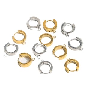 May include: A selection of gold and silver-toned hoop earrings. The earrings are small, circular, and feature a hinged clasp. Each earring has a small loop at the base. The earrings are presented against a white backdrop.