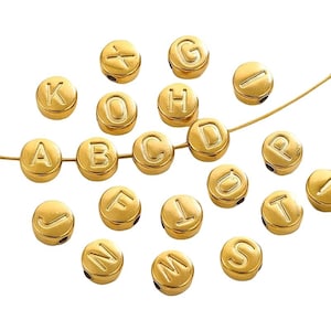 Op de afbeelding: Goudkleurige alfabetkralen, elk met een letter gegraveerd op het oppervlak. De ronde kralen zijn geregen op een dunne, goudkleurige draad. Ideaal voor het maken van sieraden of knutselprojecten.