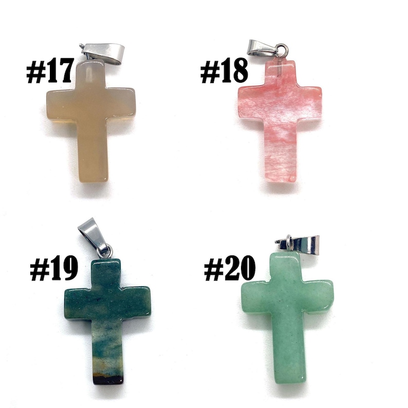 May include: Four gemstone cross pendants with silver-colored bails. The crosses are in shades of tan, pink, dark green, and light green. Each pendant is labeled with a number from #17 to #20.