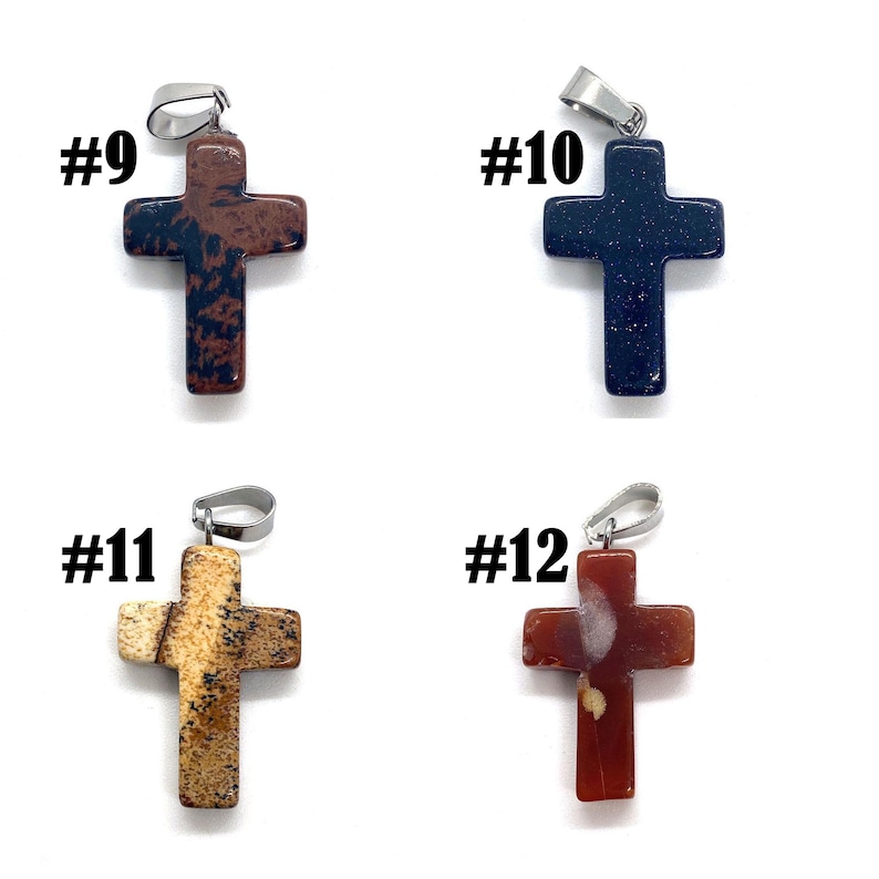 May include: Four stone cross pendants with silver-tone bails. The crosses are in various colors: brown with black spots, dark blue, tan with brown spots, and red with tan spots. Each pendant is labeled with a number.