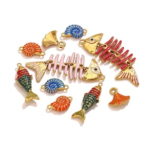 Peut inclure: Un assortiment de breloques émaillées colorées avec des motifs aquatiques. Comprend des breloques en forme d'arêtes de poisson, de poissons et de coquillages dorés en rouge, bleu, orange et vert. Idéal pour la création de bijoux ou les loisirs créatifs.