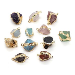 May include: Assorted gemstone pendants with gold-colored edges. The gemstones are various colors, including purple, pink, blue, green, and brown. Each pendant has two small loops for attaching to a chain or other jewelry component.