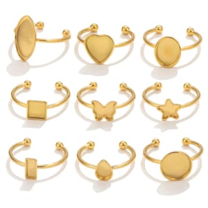 May include: Nine gold-colored adjustable rings with various shapes. The shapes include an oval, heart, circle, square, butterfly, star, rectangle, teardrop, and a round shape. Each ring has a smooth, shiny finish.