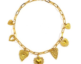 May include: A gold-colored necklace with a chain link design. The necklace features multiple heart-shaped charms in various styles, including textured and open-work designs. The necklace is displayed on a white background.