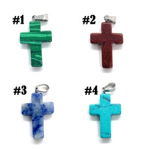 May include: Four gemstone cross pendants with silver-tone bails. The crosses are in shades of green, red-brown, blue, and turquoise. Each pendant is labeled with a number from #1 to #4.