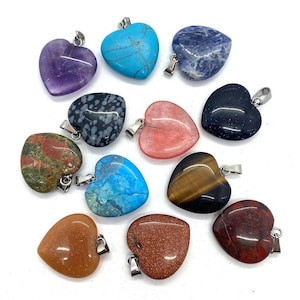 May include: A collection of heart-shaped gemstone pendants in various colors and patterns. The pendants include amethyst, turquoise, sodalite, snowflake obsidian, rose quartz, black glitter, unakite, blue turquoise, tiger's eye, carnelian, goldstone, and red jasper. Each pendant has a silver-colored bail.