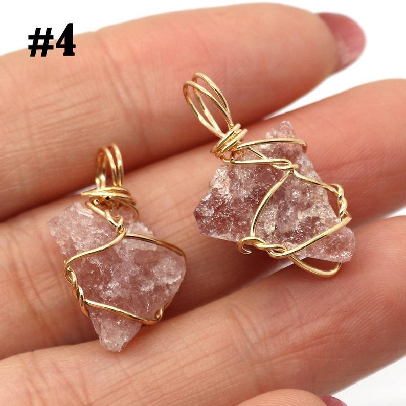 May include: Two raw, pink gemstone pendants wrapped in gold-colored wire. The gemstones have a rough, natural texture. The pendants are displayed against a blurred background. The number "#4" is in the upper left corner.