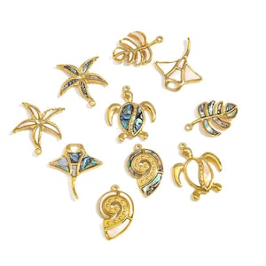May include: A selection of gold-toned charms in marine-inspired designs, such as starfish, turtles, leaves, and stingrays. Each charm incorporates iridescent abalone shell details, providing colour and sparkle. Ideal for crafting jewellery and accessories.