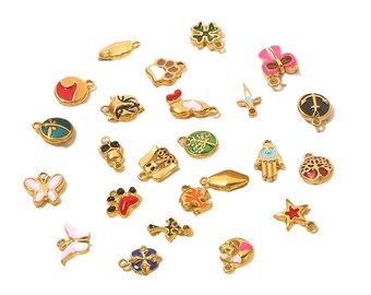 May include: A collection of gold-colored charms with various designs, including a butterfly, paw prints, a four-leaf clover, and a star. Some charms feature colorful enamel accents in red, pink, and green. The charms are scattered on a white background.