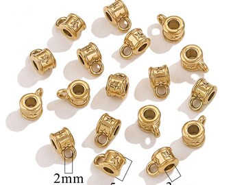 May include: Gold-colored metal charm beads with a star design. Each bead has a small handle and a cylindrical shape, with dimensions of 2mm, 5mm, and 3mm. The beads are scattered on a white surface, suitable for jewelry making.