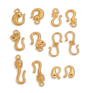 Könnte beinhalten: Eine Sammlung goldfarbener Verschlüsse in verschiedenen Designs. Die Verschlüsse weisen verzierte Details auf, darunter Tier- und Blumenmotive. Die Verschlüsse sind in verschiedenen Formen und Größen erhältlich, geeignet für die Schmuckherstellung oder Bastelprojekte.