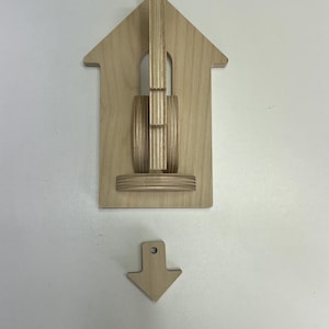 May include: Wooden wall art featuring a guitar design within a house-shaped frame. The guitar is constructed with layered wood, and a separate arrow-shaped piece is included. The art is made of natural wood.
