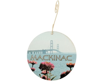 May include: A round wooden bauble featuring a picture of the Mackinac Bridge and pink flowers. The bauble has a gold hanger.