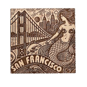 Puede incluir: Un posavasos de madera con un diseño marrón y blanco que presenta el Puente Golden Gate, una sirena y el texto "SAN FRANCISCO".