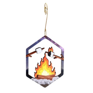 Op de afbeelding: Een zeshoekige houten ornament met een sterrenhemel als achtergrond. In het midden van de ornament bevindt zich een kampvuur met vlammen en twee marshmallows op stokken.
