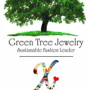 The image is a promotional poster for a jewelry brand called "Green Tree Jewelry". It features a large green tree with a heart symbol in the center, and the text "Green Tree Jewelry Sustainable Fashion Leader" is displayed above the tree. The poster also mentions a "Frage X Awareness Mission Leading Inherited Cause of Autism".