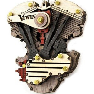 May include: Wooden V-Twin engine pendant with a detailed design. The pendant features a mix of light and dark wood, with red and gold accents. The text "V TWIN" is visible on the top. The pendant is attached to a black beaded chain.