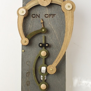 Peut inclure: Un interrupteur lumineux en bois avec un design unique. L'interrupteur a un levier qui se déplace vers la gauche ou la droite pour allumer ou éteindre la lumière. L'interrupteur est étiqueté "ON OFF" et a un design décoratif.