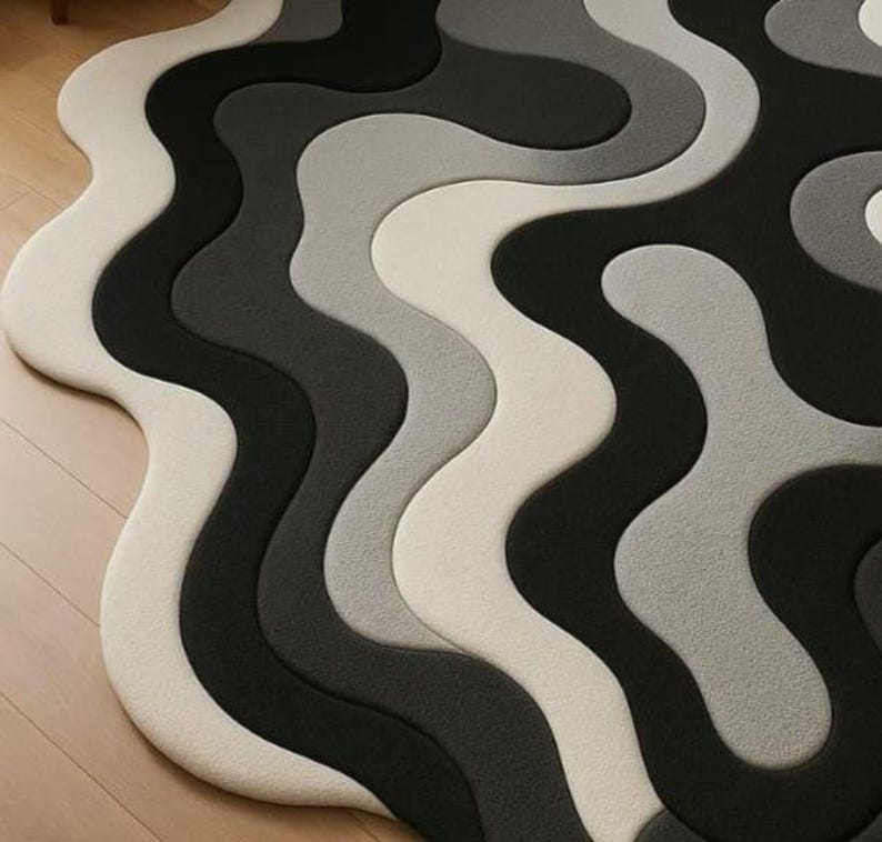 May include: A modern area rug with a wavy, abstract design. The rug features a pattern of flowing, interconnected shapes in shades of white, gray, and black. The rug's design creates a sense of movement and visual interest, suitable for contemporary home decor.