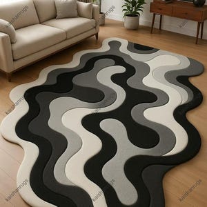 May include: A modern area rug with a unique, flowing design. The rug features a wavy pattern in shades of black, gray, and white. The rug's shape is irregular, adding to its contemporary aesthetic. This floor covering is suitable for living rooms and bedrooms.