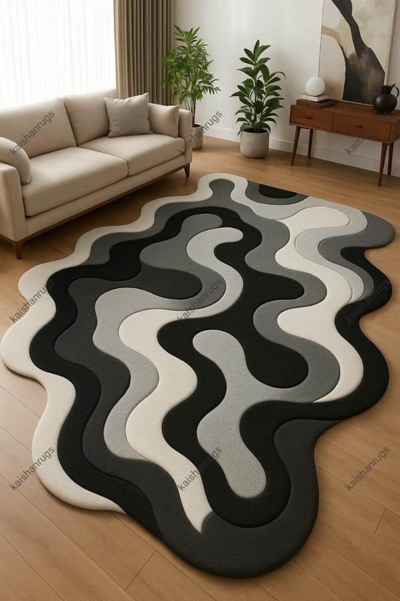 May include: A modern area rug with a unique, flowing design. The rug features a wavy pattern in shades of black, gray, and white. The rug's shape is irregular, adding to its contemporary aesthetic. This floor covering is suitable for living rooms and bedrooms.