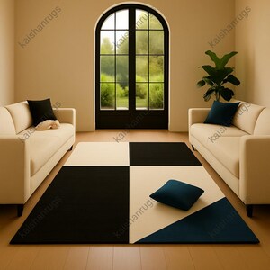 May include: A contemporary geometric rug in black, white, and navy blue. The rug has a checkerboard design with a triangular section. Two cream-coloured sofas and two black cushions are also visible in the room.