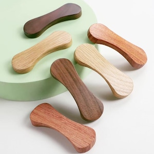 Może przedstawiać: Zestaw trzech ceramicznych kubków z nakrapianym, matowym wykończeniem. Kubki są w odcieniach kremu, jasnoszarym i ciemnoszarym. Każdy kubek ma prosty, minimalistyczny design.