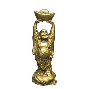 May include: A gold-colored standing figurine of a smiling, round-bellied figure with arms raised above the head, holding a boat-shaped ingot. The figure wears loose robes and a beaded necklace, standing on a textured, rounded base.