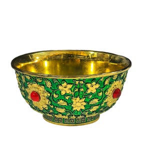 May include: A decorative bowl featuring a bright green exterior with raised gold floral patterns and embedded red circular stones. The interior is finished in a polished gold tone, and the base is decorated with a black and gold geometric Greek key border.
