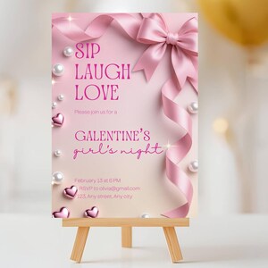May include: A pink Galentine's Day invitation on a small wooden easel. The invitation features pink text that reads "SIP LAUGH LOVE" and "GALENTINE'S girl's night." The design includes a pink ribbon, pearls, and heart accents.